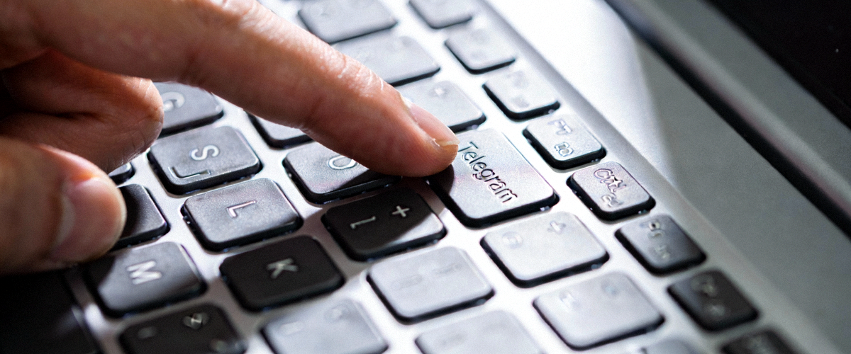 特写镜头展示用户手指在笔记本电脑键盘上操作Telegram快捷键